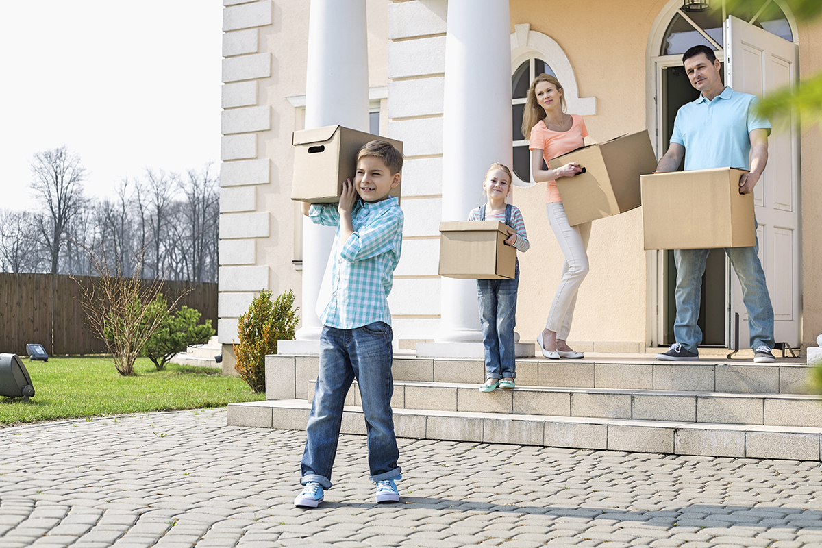 Family with cardboard boxes moving out from house